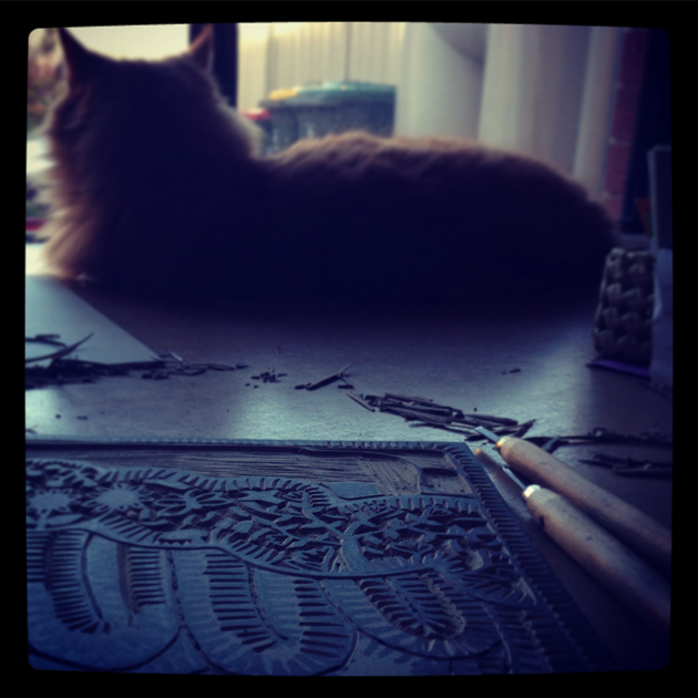 Orange Cat beside a carved lino print in progress